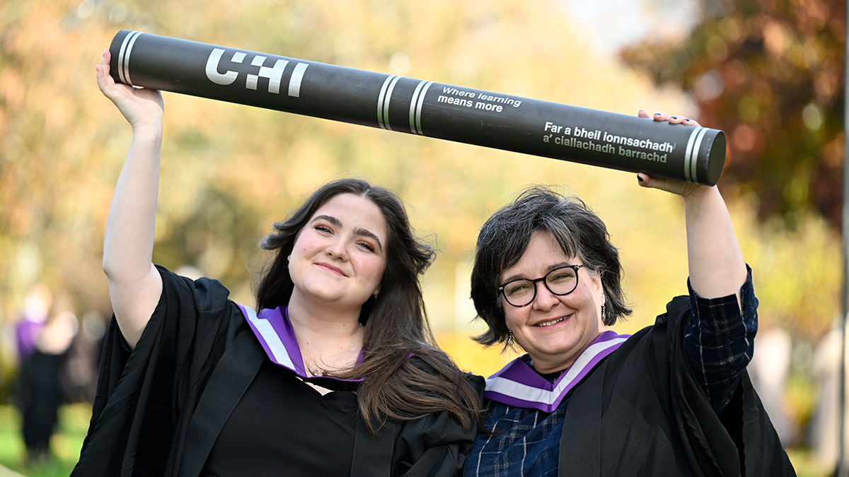 Alix and Margaret Aburn in gowns holding giant scroll
