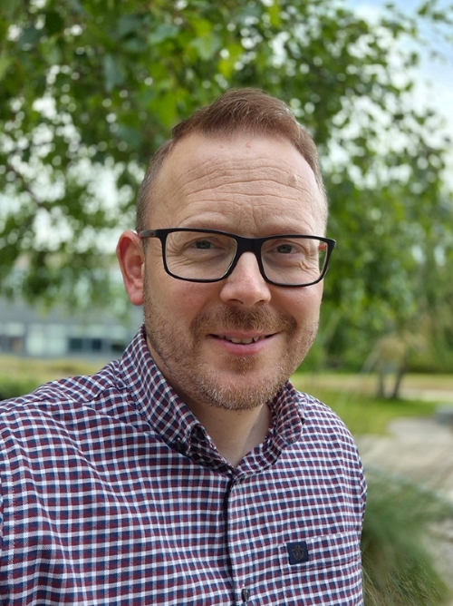 Matt Tyrer smiling at the camera in an outdoor campus setting