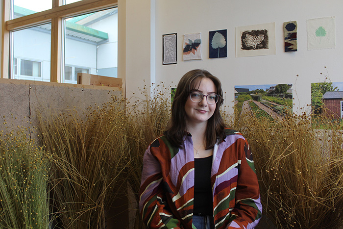 Fine art graduate Alex Muir in the studio with their artwork behind them