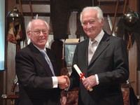 Two people shaking hands posing for the camera wearing formal business attire