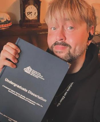 Man holding a book. Cover reads: Undergraduate dissertation