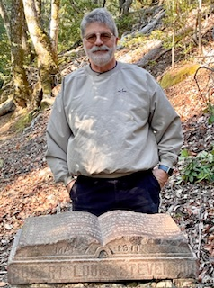 Lecturer Jimm Simon standing behind Robert Louis Stevenson memorial