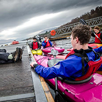 People sitting in Kayaks next to a jetty People sitting in Kayaks next to a jetty