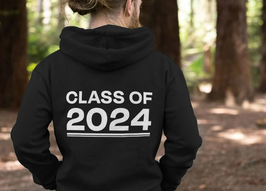 A man standing in the woods, with his back to the camera and his hoodie says 'Class of 2024 A man standing in the woods, with his back to the camera and his hoodie says 'Class of 2024